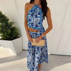 Woman wearing a blue floral dress holding a clutch in an outdoor setting.