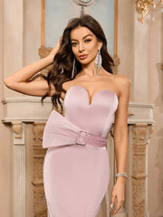 Woman wearing a light pink strapless dress with a belt in an elegant indoor setting.