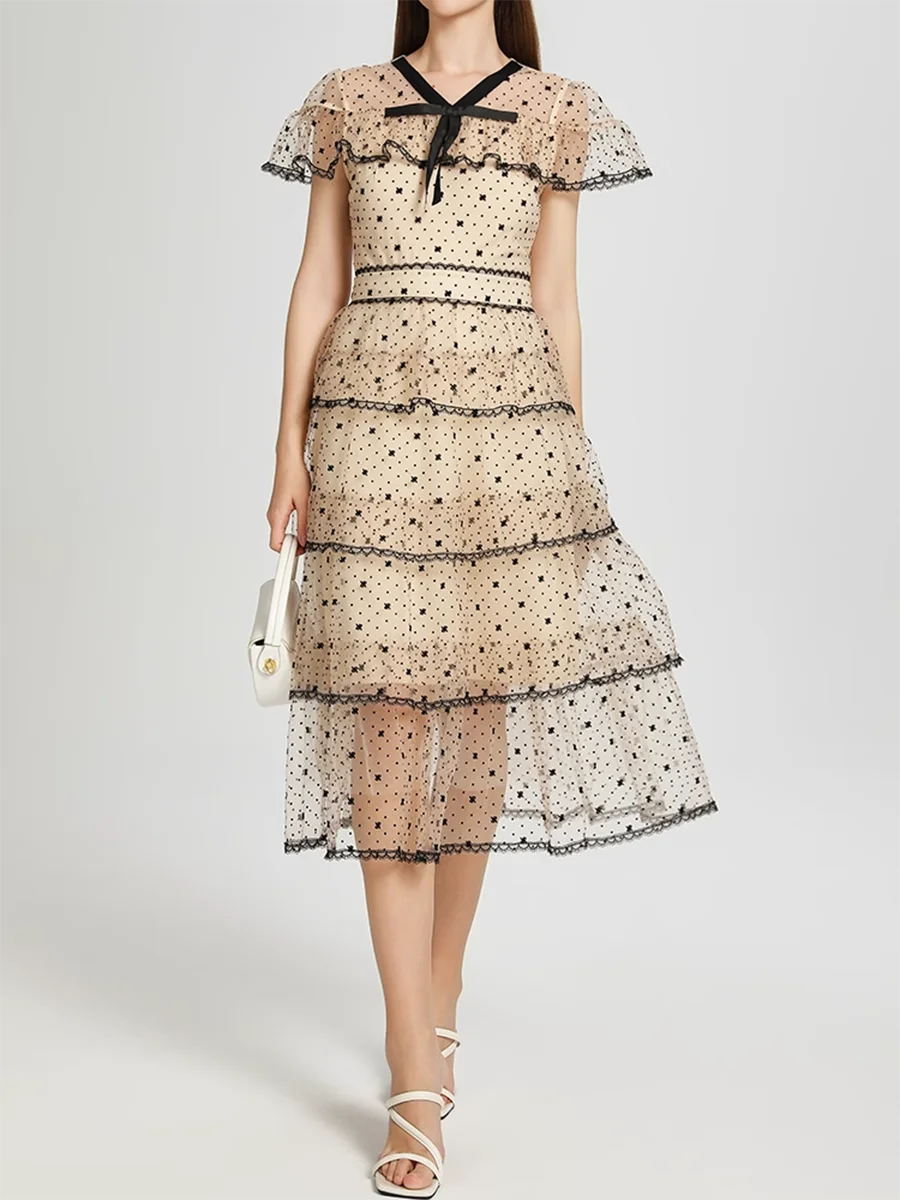 Woman wearing a tiered lace dress with a plain background