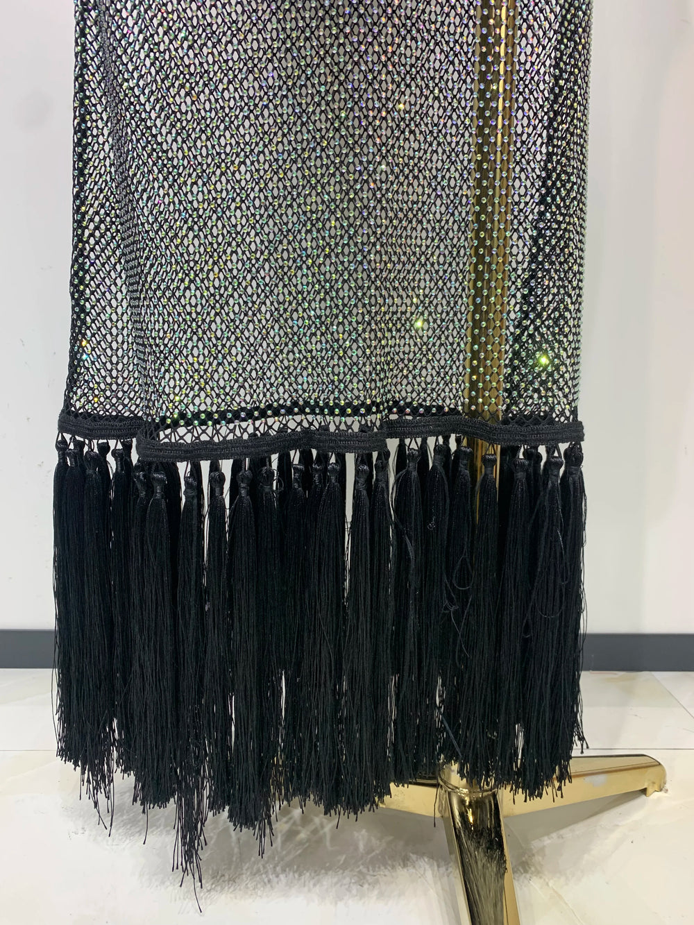 Black fringe garment on a mannequin against a white background