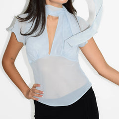 Woman wearing a light blue blouse with ruffled sleeves on a white background