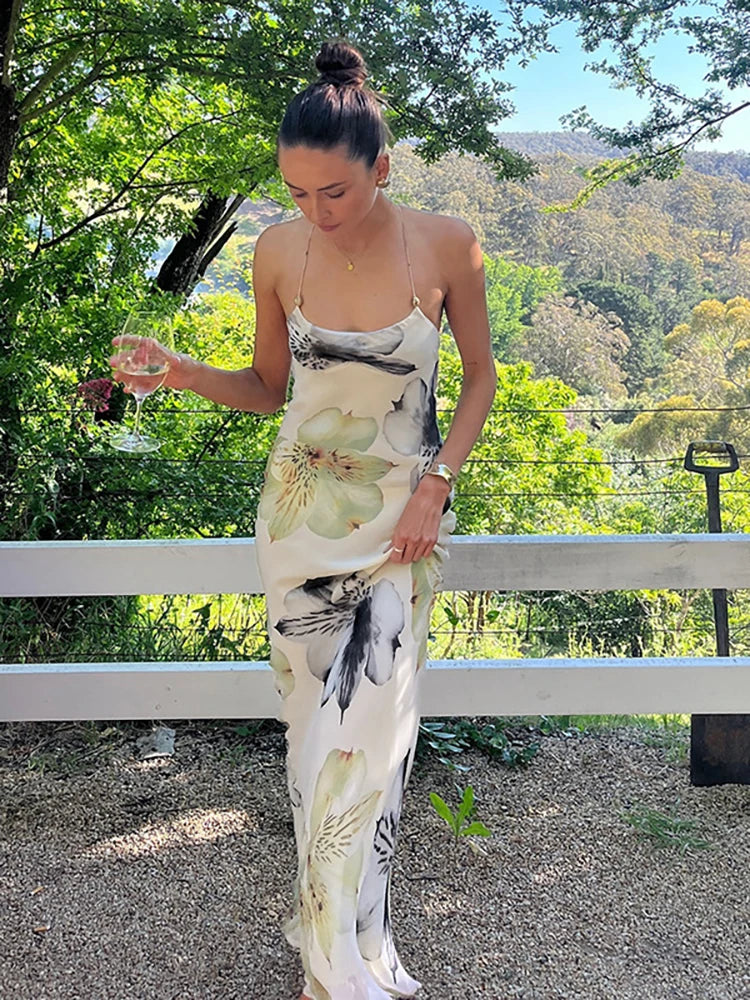 Woman in a floral dress standing outdoors with greenery in the background
