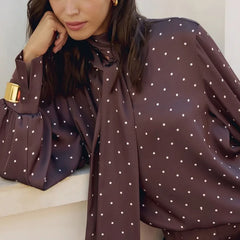 Woman wearing a brown polka dot blouse with a white background
