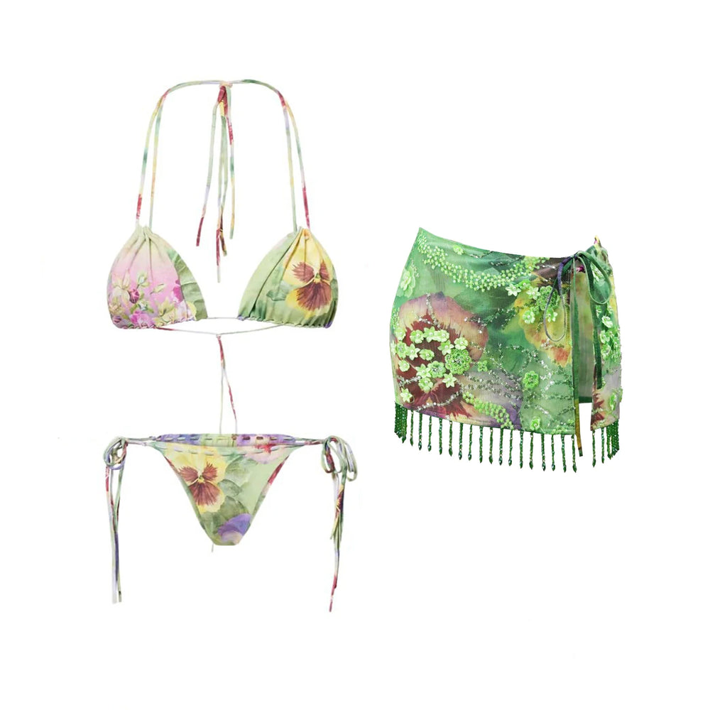 Floral print bikini and green beaded skirt laid flat.