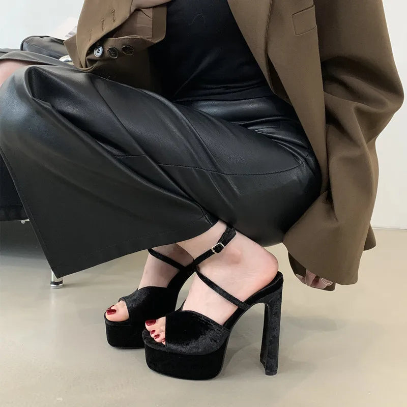 Person wearing black platform high-heeled shoes with a neutral background