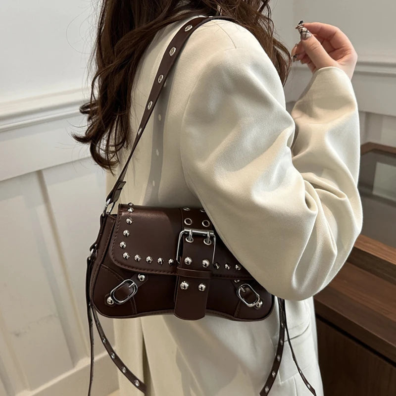 Person wearing a white sweatshirt with a brown studded handbag.