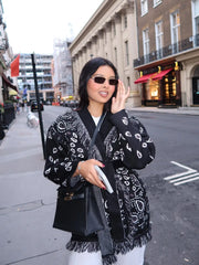 Woman wearing a black patterned coat on a city street