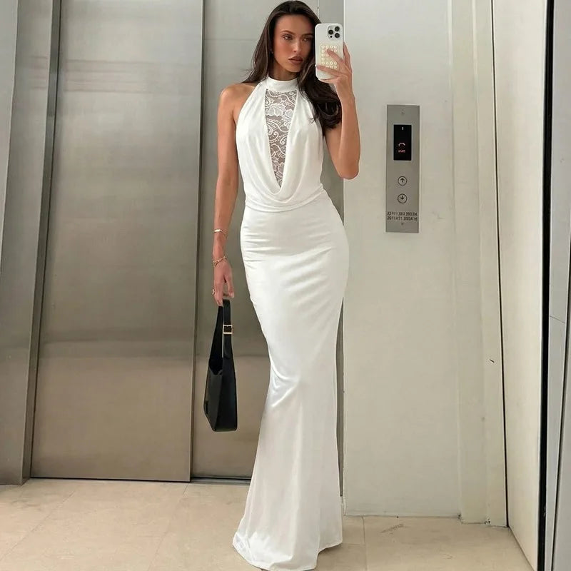 Woman in a white evening gown taking a mirror selfie in an elevator.