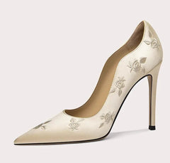 Beige high-heeled shoe with floral embroidery on a light gray background