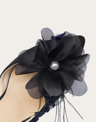 Navy blue floral shoe detail with a pearl on a white background