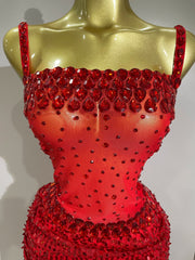 Red beaded top on a gold mannequin against a gray background