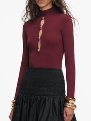 Maroon long-sleeve top with cut-out design and black skirt on a white background
