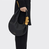 Black grained leather half moon shoulder bag with sculpted gold face hardware detail