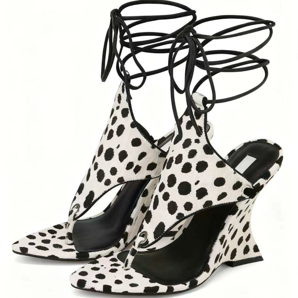 Black and white polka dot high-heeled shoes with strappy design on a white background