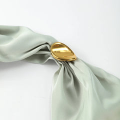 Gold napkin ring on a folded green napkin against a white background