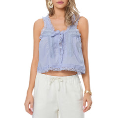 Woman wearing a light blue lace-trimmed top and white pants on a white background