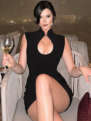 Woman in a black dress holding a glass of wine on a rooftop at night.