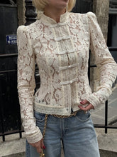 Person wearing a lace blouse with long sleeves and a high collar, standing outdoors.