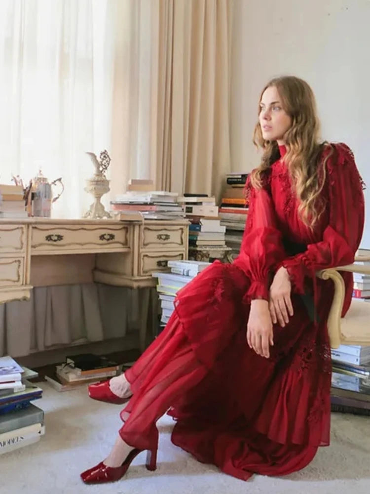 Woman in a red dress sitting in a room with books and a desk.