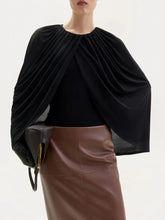 Black draped top worn by a person with a white background