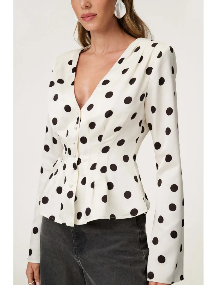White blouse with black polka dots worn by a person on a white background