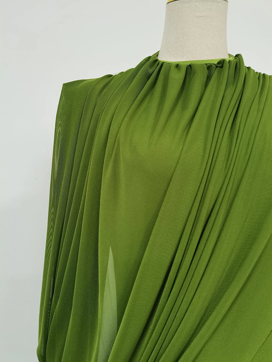 Green fabric draped over a mannequin on a white background