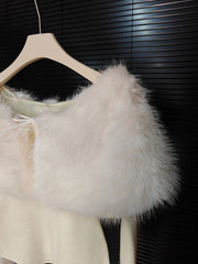 White fur shrug draped over a white garment on a hanger against a dark background