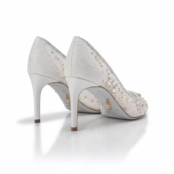 Pair of silver high-heeled shoes with intricate detailing on a white background