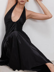Woman wearing a black halter neck dress against a white background