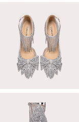 Silver high-heeled shoes with fringe details on a light pink background