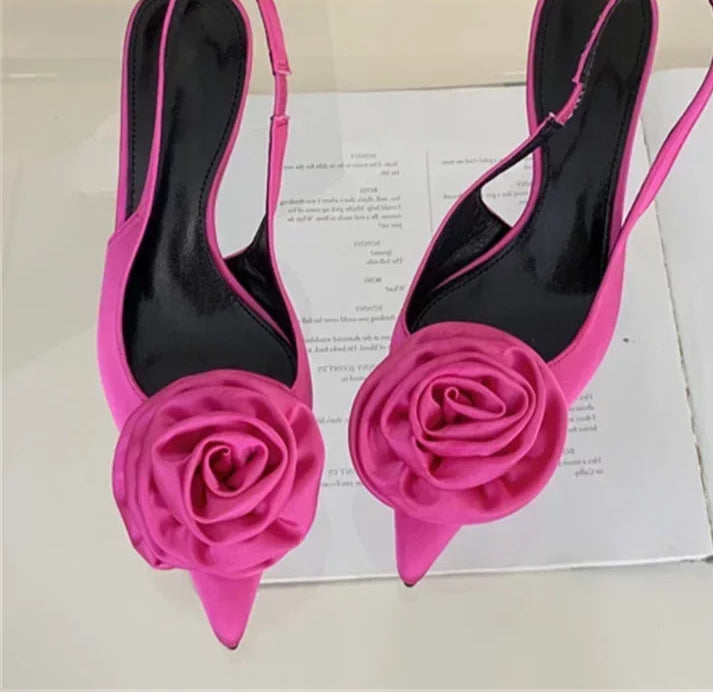 Pink high-heeled shoes with floral design on a white surface