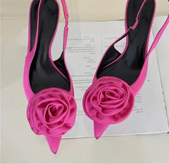 Pink high-heeled shoes with floral design on a white surface
