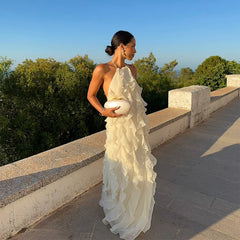 Woman in a white ruffled dress standing on a stone pathway with greenery in the background
