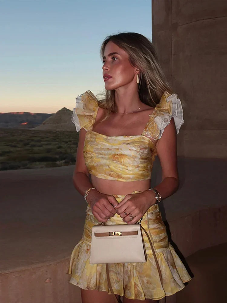 Woman in a yellow dress holding a beige handbag against a desert landscape.