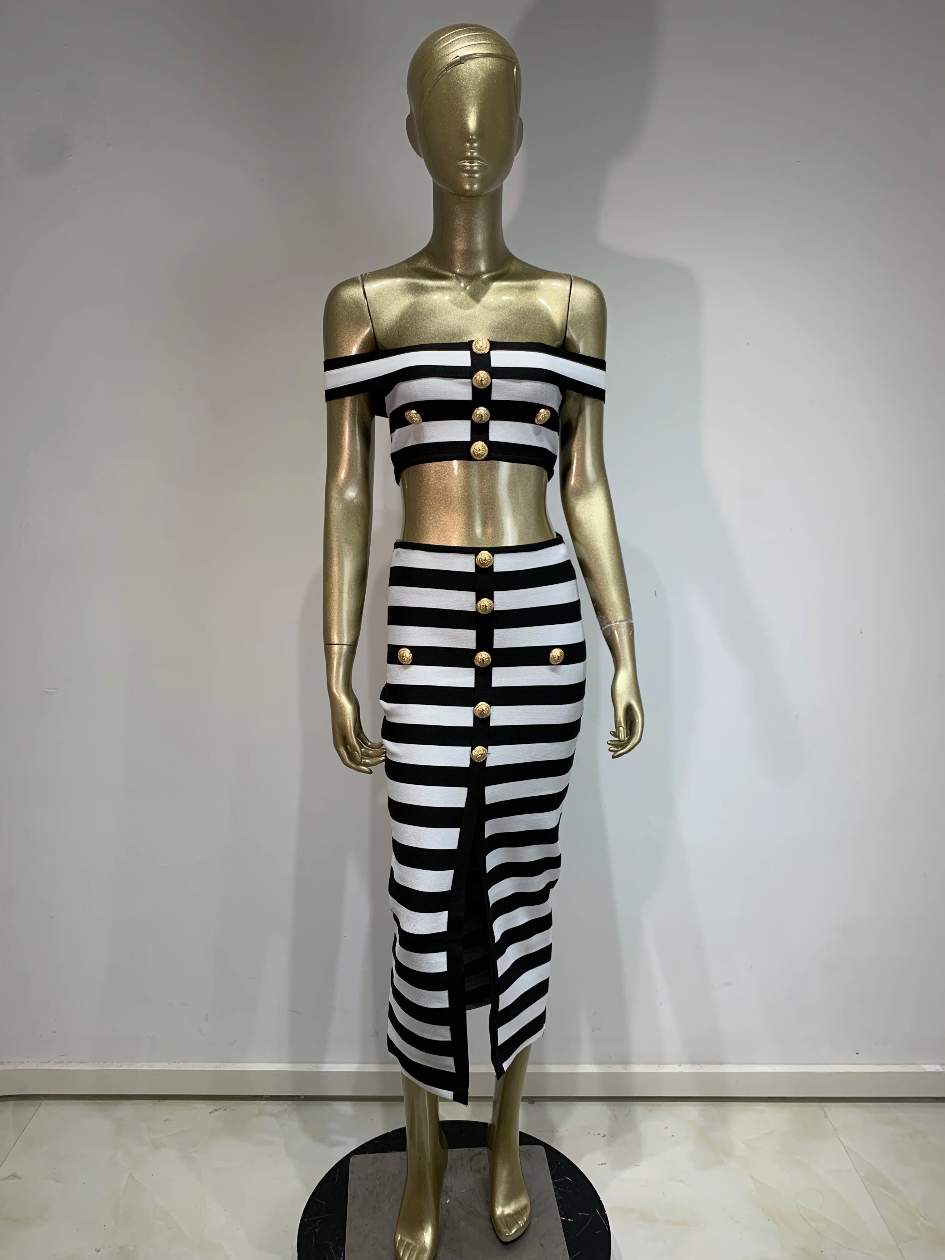 Mannequin wearing a black and white striped outfit with gold buttons against a plain background