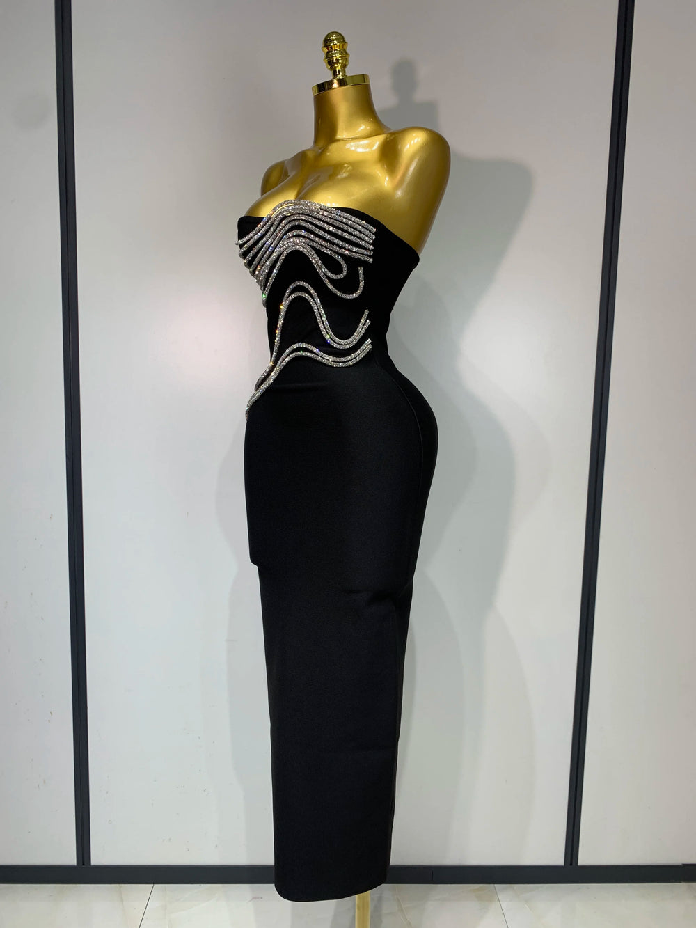 Black strapless dress with bead embellishments on a mannequin against a plain background