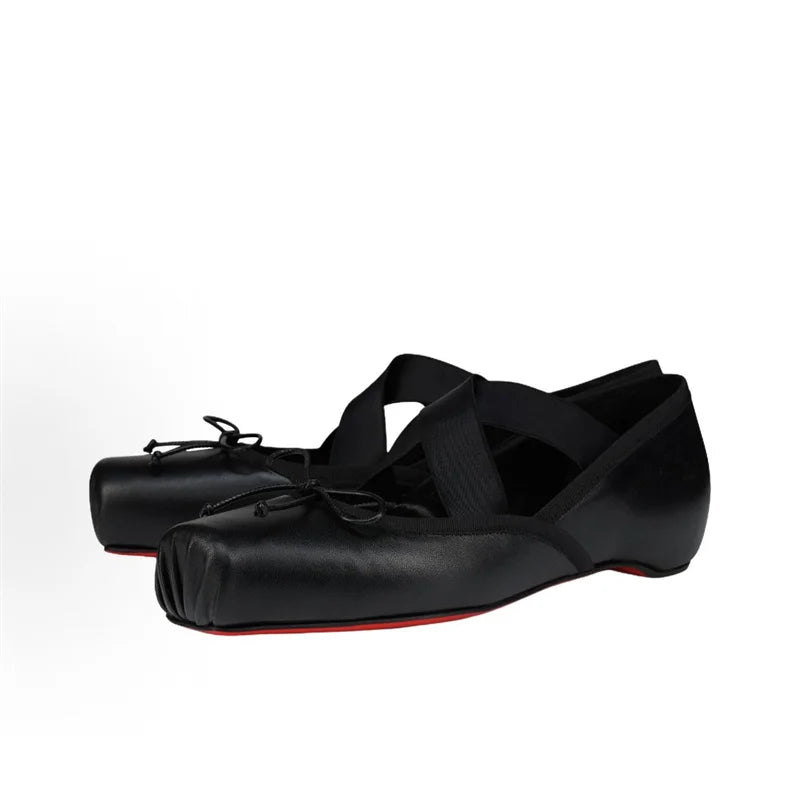 Black ballet shoes with red soles on a white background