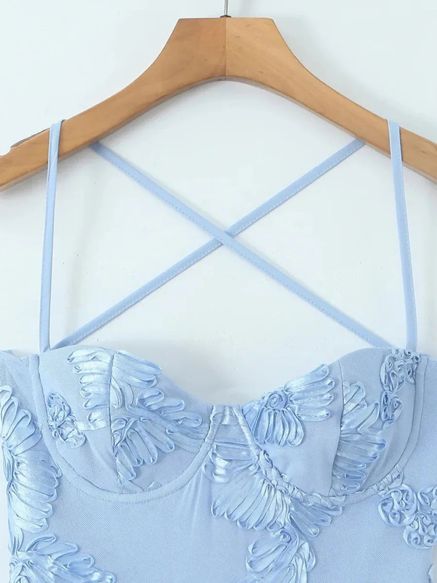 Light blue strappy top with floral embroidery on a wooden hanger against a white background