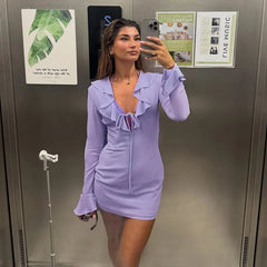 Woman wearing purple ruffled v-neck mini dress in elevator