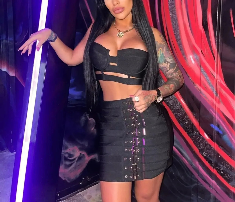 Woman in a black outfit posing against a colorful, abstract background