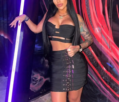 Woman in a black outfit posing against a colorful, abstract background