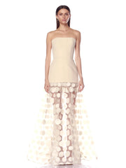 Woman wearing a strapless dress with a sheer, circular patterned overlay on a white background