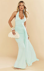 Woman wearing a light blue halter neck dress against a beige background