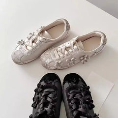 Overhead view of light grey sneakers alongside black sneakers with floral details.