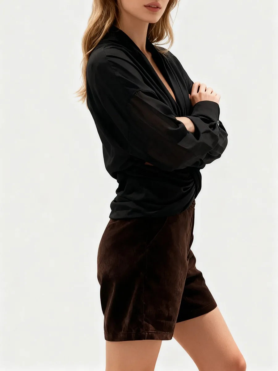 Woman wearing a black top and brown shorts on a white background