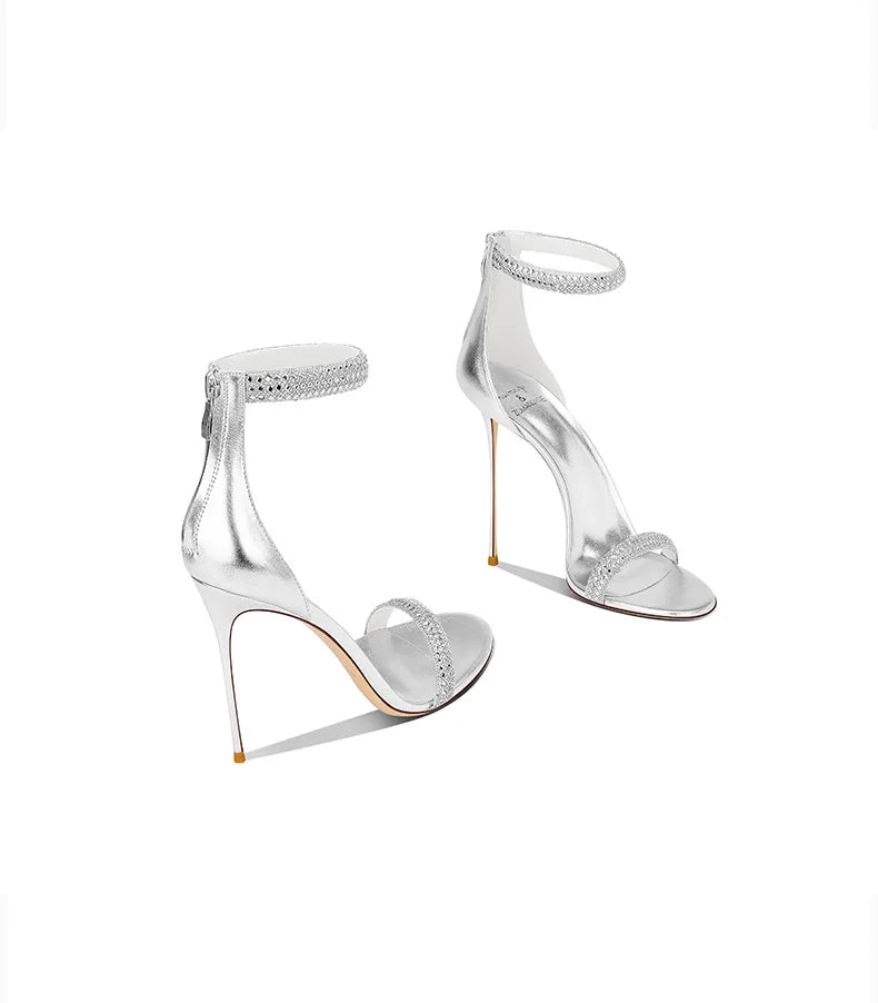 Silver high-heeled shoes with clear straps on a white background