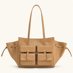 Tan handbag with multiple pockets and drawstrings on a white background