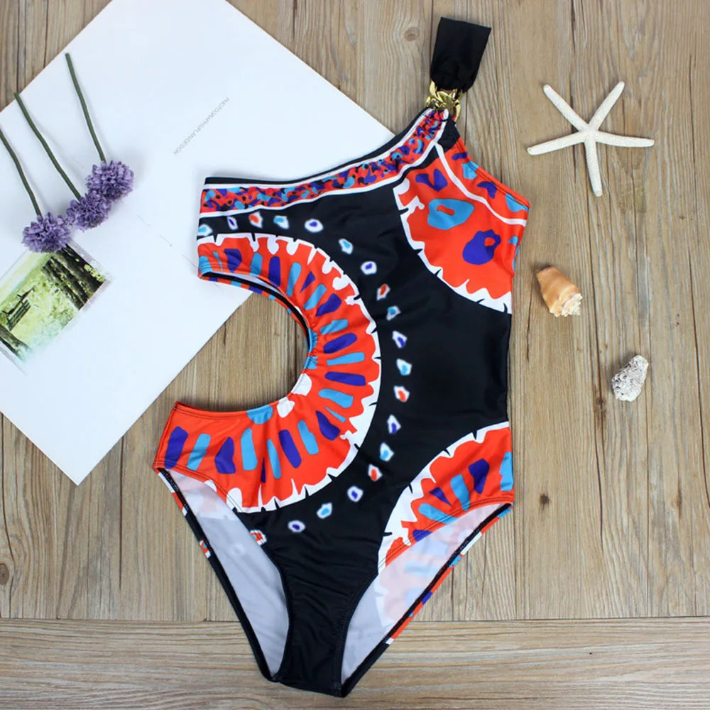 View of a one-piece swimsuit laid flat, showcasing its one-shoulder cut and vibrant pattern.