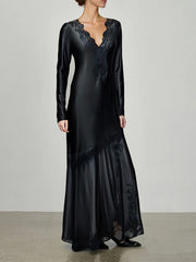 Black satin evening gown with lace details on a plain background