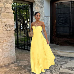 Woman in a yellow dress standing outside a stone building.